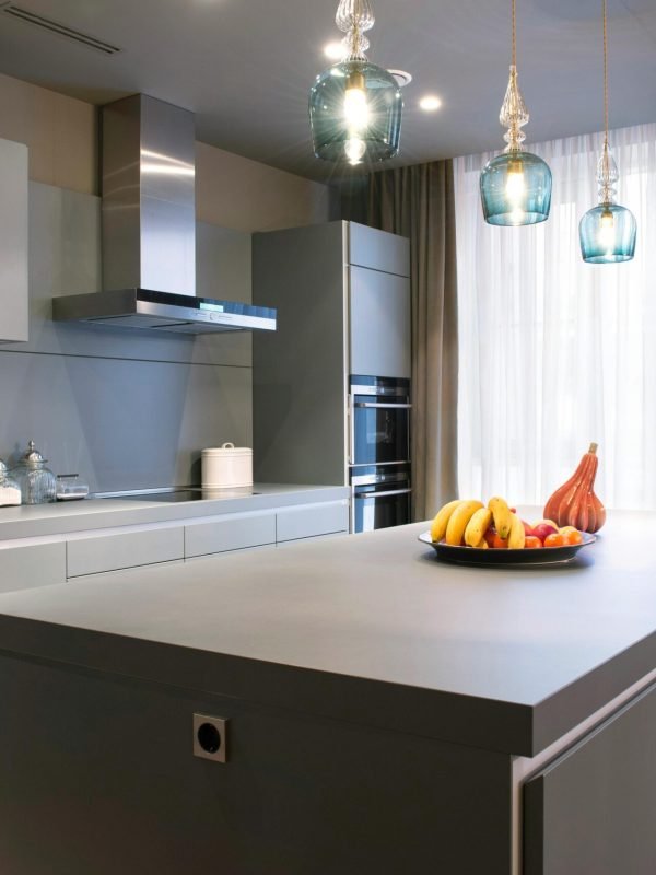 Sleek modern kitchen interior featuring a large island, elegant pendant lights, and fresh fruit decor.